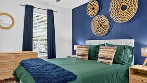 A bedroom with a bed, a nightstand, a dresser, and a window with curtains.
