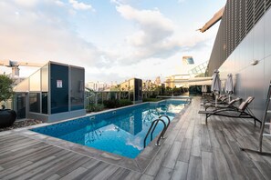 A rooftop pool with a modern design, including a glass enclosure and lounge chairs.