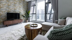 A modern living room with a large window, a flat-screen TV, a wooden coffee table, and a sofa. - LUX Waterfront 1BR near B Khalifa (Dubai)