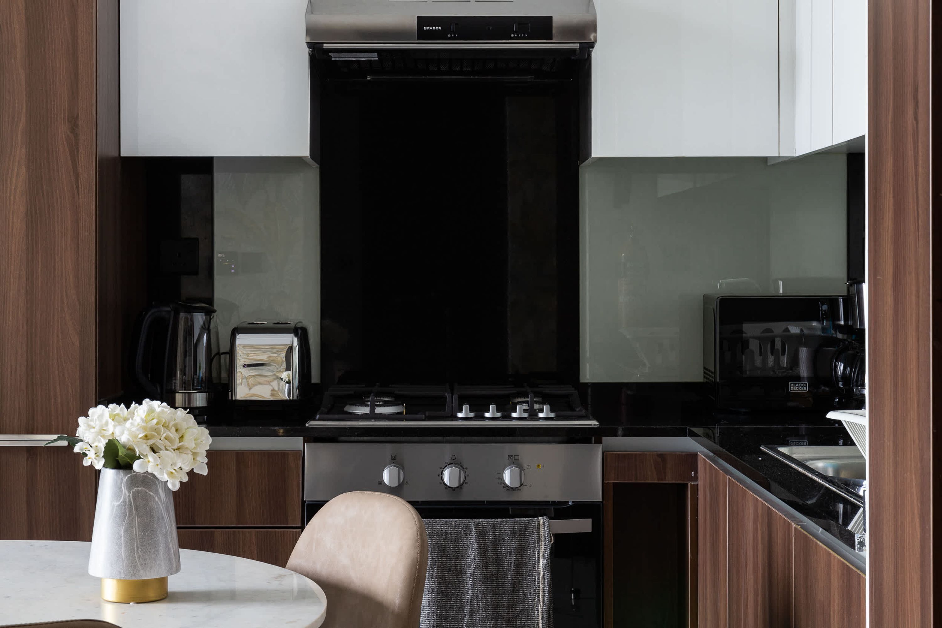 Une cuisine moderne équipée d’une cuisinière, de placards et d’un vase rempli de fleurs posé sur le plan de travail.