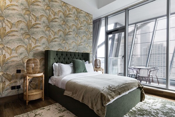 A bedroom with a large bed, a window with a view, and a patterned wallpaper.