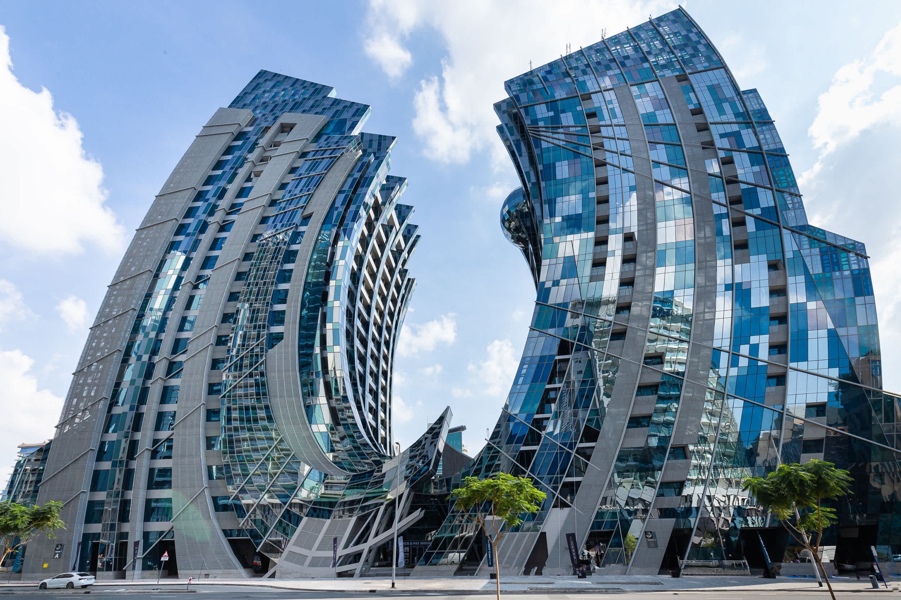 Un bâtiment moderne doté de façades en verre incurvé et d’une surface réfléchissante.