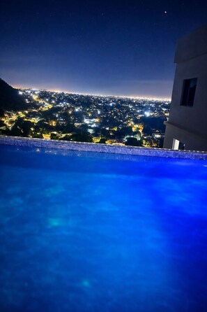 Una piscina con vista a la ciudad de noche.