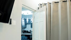 Een moderne keuken met witte kasten, een zwart aanrecht en een blauwe stoel.