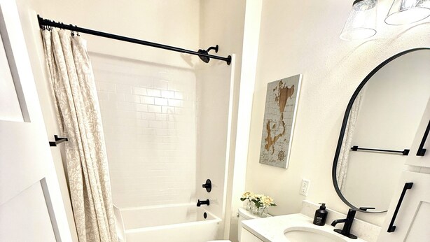 A bathroom with a bathtub, toilet, and sink. - Modern 3-Story Condo Across from Arnold’s Park – Walk to Fun, Lake, & Dining! (Arnolds Park)