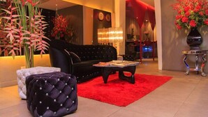 Un salon moderne avec un canapé noir, un tapis rouge et des plantes décoratives.