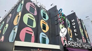 La façade d’un hôtel, ornée de motifs colorés sur les fenêtres, avec le nom «The Ardens Hotel» affiché en évidence.