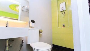 Une salle de bain avec des toilettes blanches, un lavabo avec un miroir et un espace douche.