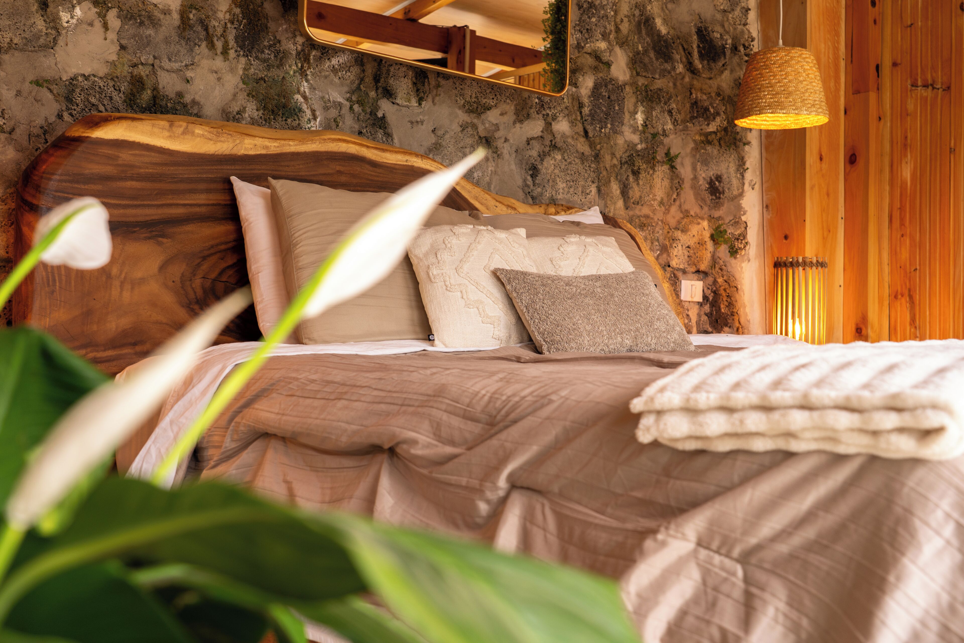 Un lit avec une tête de lit en bois, plusieurs oreillers et une couverture.