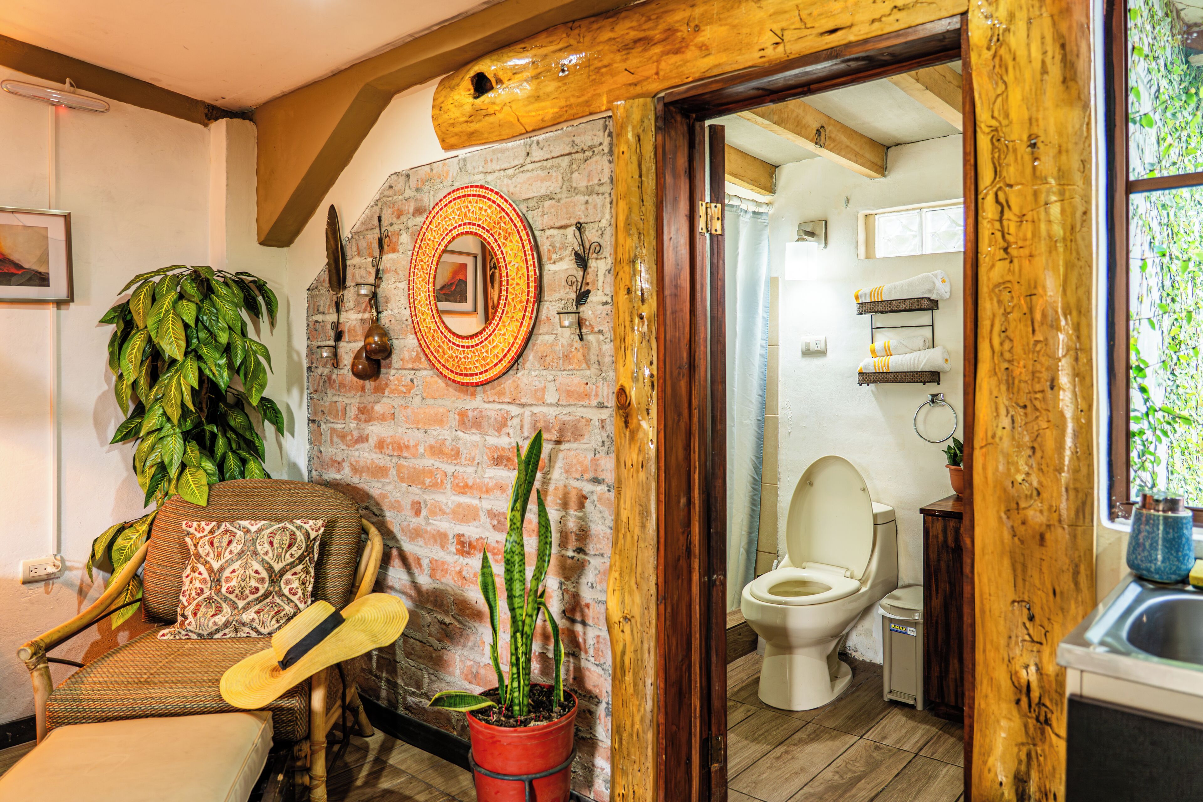 Un baño rústico con techo de madera, pared de ladrillo, inodoro y lavamanos.