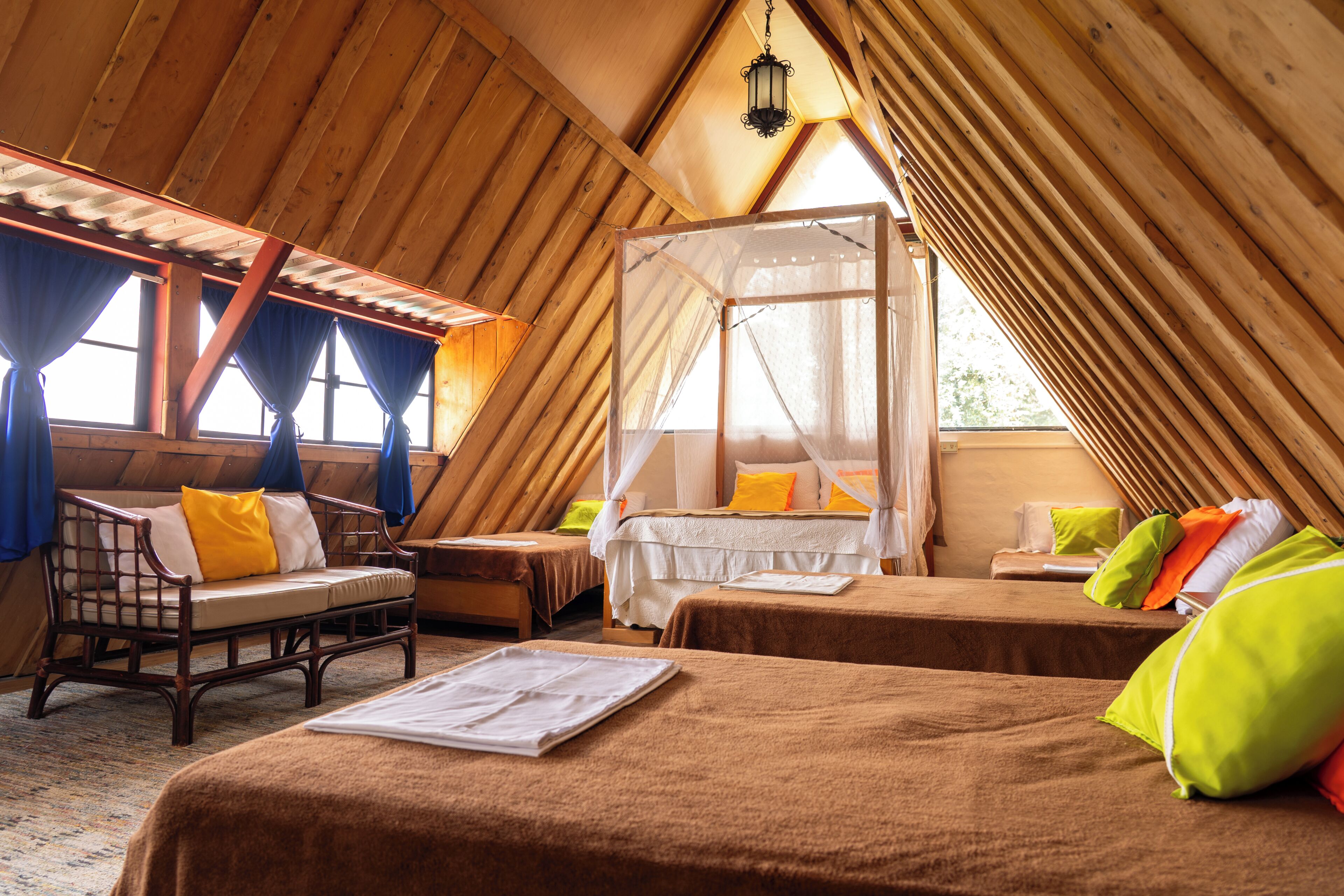 A cozy, wooden-roofed room with a bed, a wooden bench, and a small table.