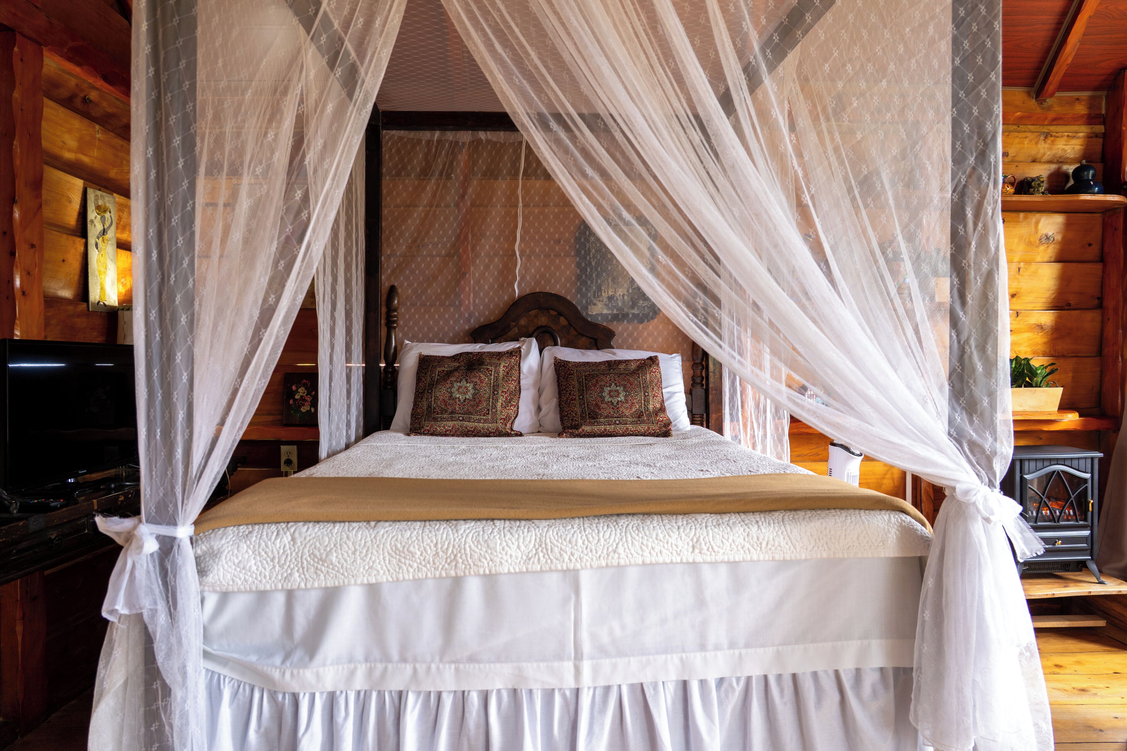 A bed with a canopy, a wooden headboard, and decorative pillows.