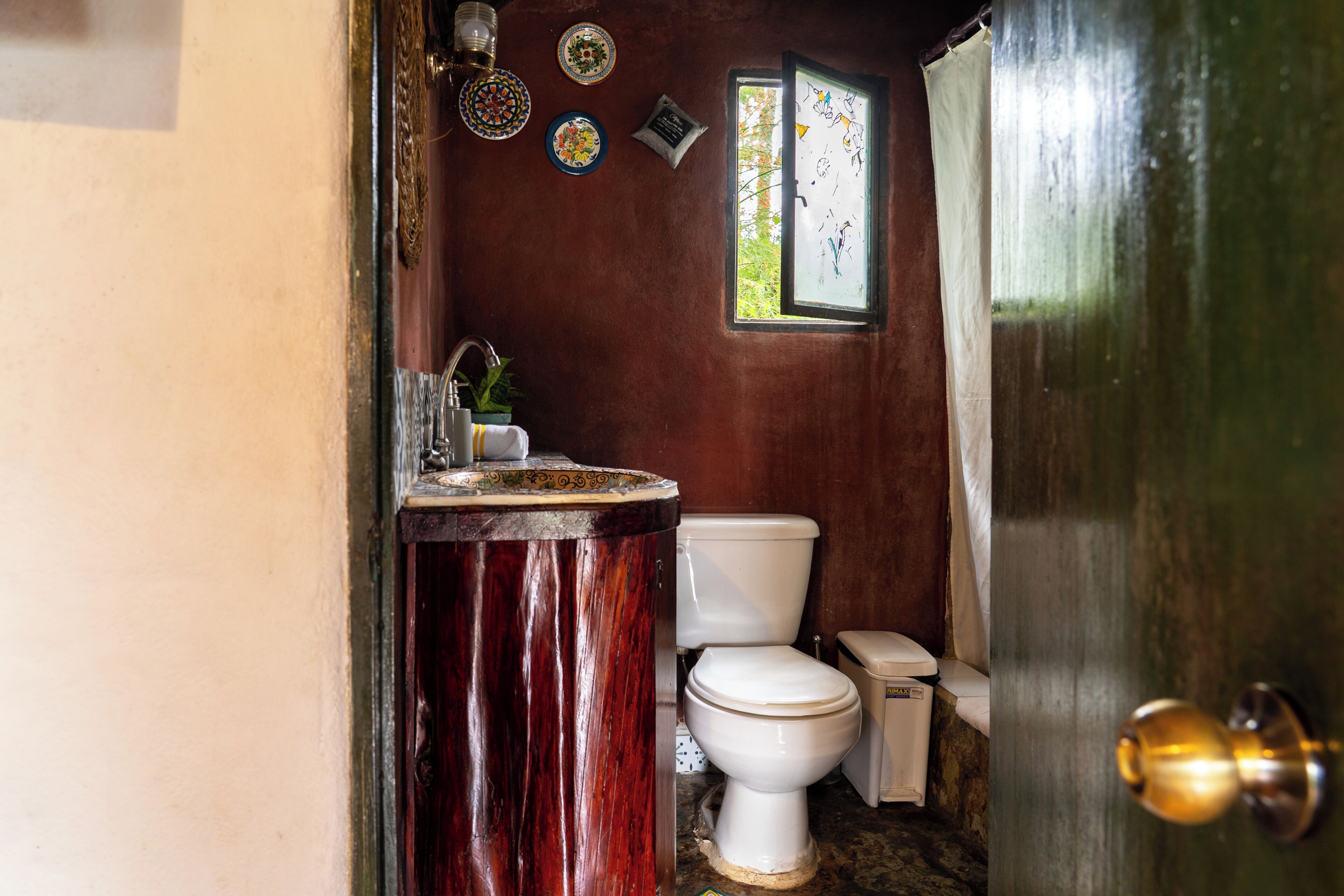 Un baño con tocador de madera, inodoro blanco y ventana con vistas.
