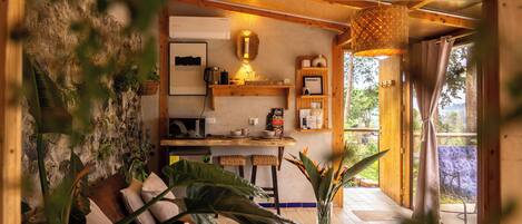 Un interno accogliente con soffitto in legno, un'area pranzo con tavolo e sedie, e un'ampia finestra con vista.
