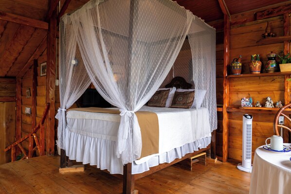 Een houten slaapkamer met een hemelbed, een nachtkastje met een kopje, en een verwarming.