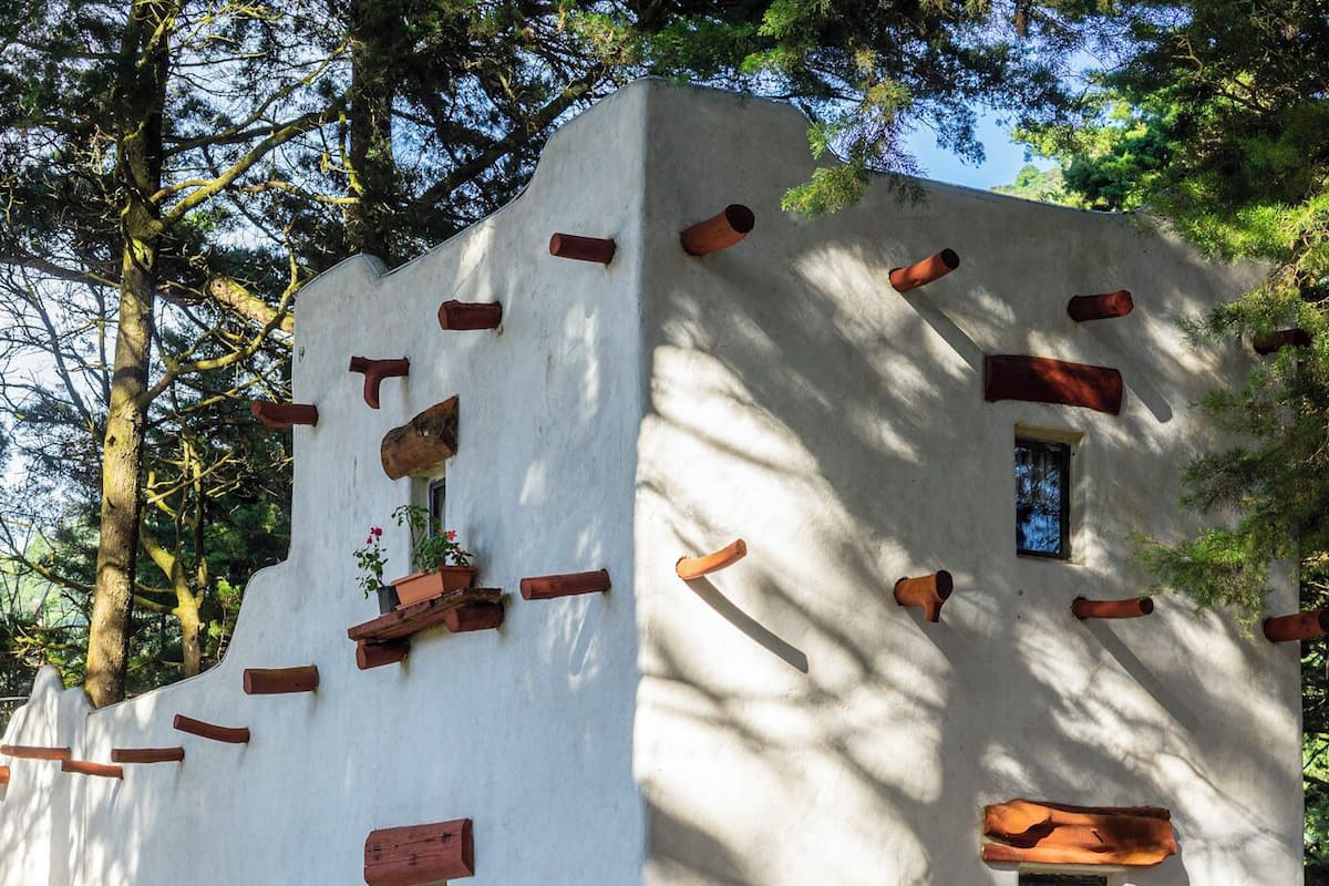 Un bâtiment de style rustique, avec une façade blanche, des éléments décoratifs en bois et des plantes en pot.