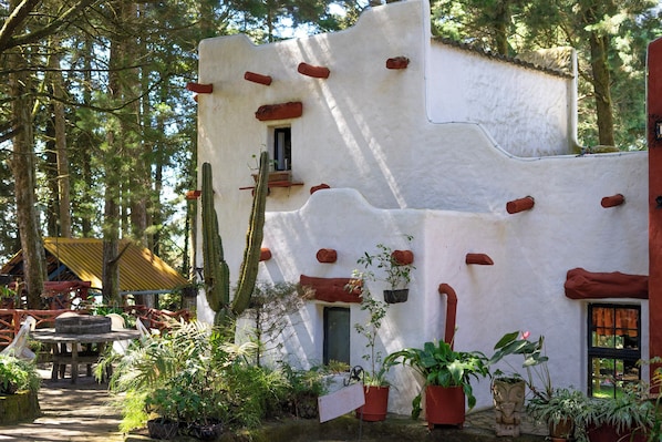 Un bâtiment de style rustique, avec une façade blanche, des éléments décoratifs rouges et une porte en bois.