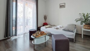 A bedroom with a bed, a glass table with a tray of items, a potted plant, and a window with curtains. - Sunset Apartment With Panoramic Sea View, Senj, Croatia (Senj)