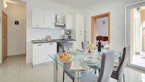 A modern kitchen with white cabinets, a glass dining table, and a view to the outside.