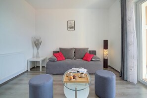 A modern living room with a grey sofa, red cushions, a glass coffee table with a tray of items, and a side table with a vase. - Comfy Apartment With Panoramic Sea View, Senj, Croatia (Senj)