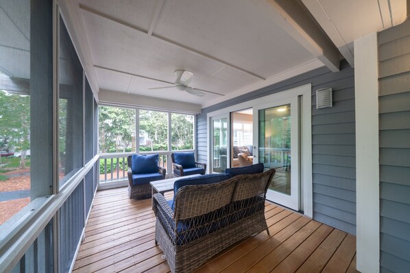 A covered porch with wicker furniture and a ceiling fan.