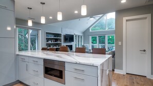 Una cocina moderna con una isla grande, electrodomésticos integrados e iluminación colgante.