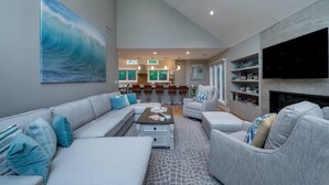 Una sala de estar moderna con un sofá gris, una mesa de centro y una chimenea. Hay un cuadro grande en la pared y un televisor montado.