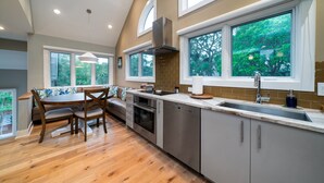 Una cocina moderna con comedor, ventanas amplias y vistas a zonas verdes.