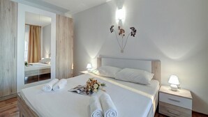 A hotel room with a large bed, a nightstand with a lamp, a mirror, and a wall-mounted light fixture. - Comfy Sunset And Sea View Apt /w Jacuzzi, Senj, Croatia (Senj)