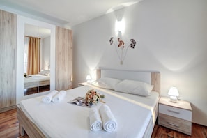 A hotel room with a large bed, two bedside tables, a mirror, and a wall-mounted light fixture. - Comfy Sunset And Sea View Apt /w Jacuzzi, Senj, Croatia (Senj)