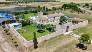 Vista aérea de una propiedad con piscina, muros de piedra y una mezcla de arquitectura moderna y tradicional.