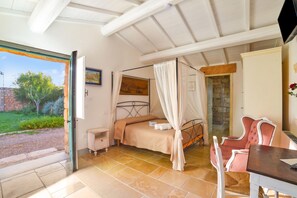 A bedroom with a bed, a chair, a desk, and a view of the outdoors.