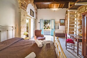 A bedroom with a bed, a chair, a desk, and a view of the outside. - Masseria Santu Lasi with Private Pool & BBQ, Surbo, Italy (Surbo)