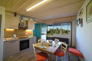 A modern kitchen with wooden cabinets, a built-in oven, and a dining area with a wooden table and chairs.