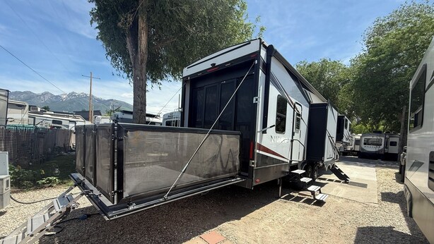Un veicolo ricreativo (RV) dotato di una porta scorrevole, una piccola piattaforma rialzata e una zona coperta.