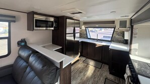 Una cucina compatta con forno a microonde, frigorifero e una finestra che si affaccia su un parcheggio.