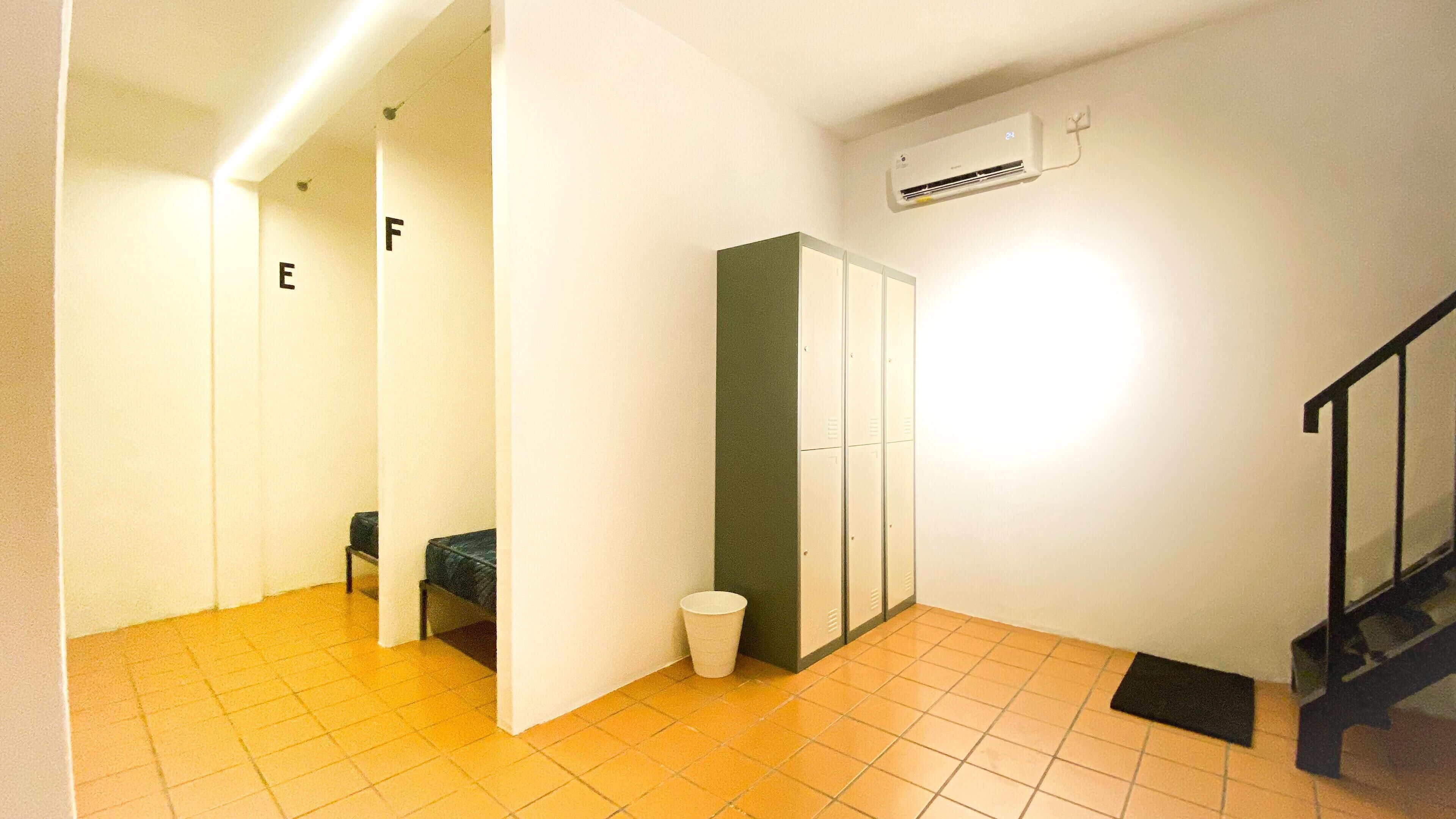 A hallway with lockers, a trash bin, and a staircase.