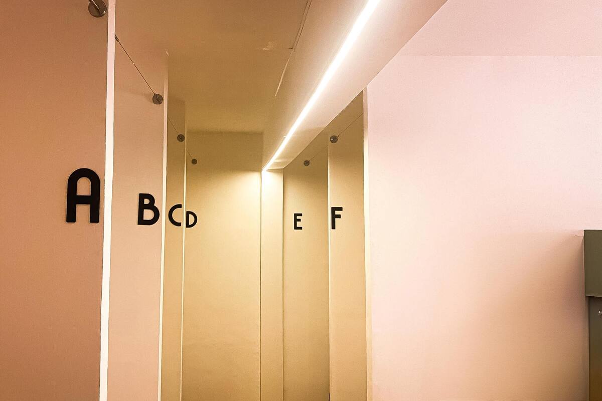 Un couloir intérieur dont les murs sont ornés des lettres A, B, C, D, E, F, indiquant les différents étages.