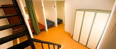 Una escalera que conduce a una habitación con una cama, un armario y una cortina verde.