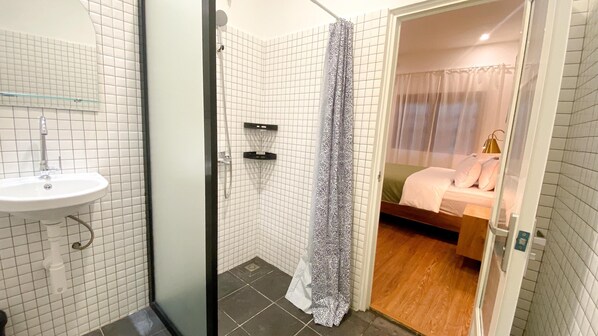 A bathroom with a sink, shower, and a bed with a canopy. - Huma Yogyakarta Hostel (Yogyakarta)