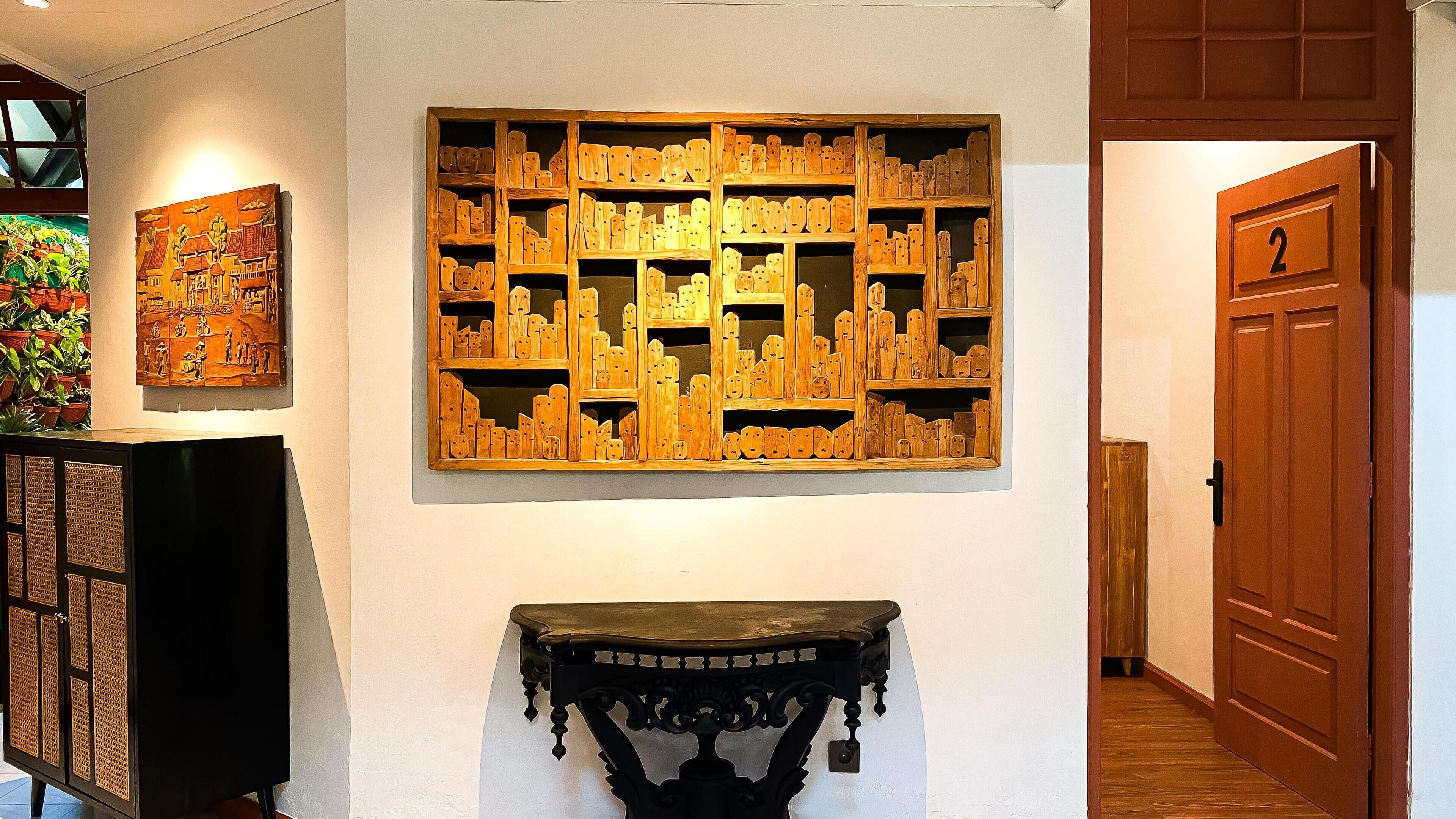 A hallway with a wooden wall art piece, a black console table, and a door marked with the number 2.