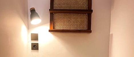 A single bed with a wooden headboard, a woven headboard above it, and a wall-mounted light fixture.