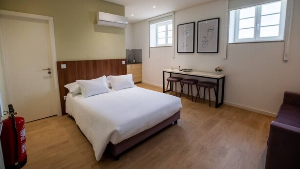 Une chambre avec un lit, un bureau et une chaise. Un extincteur est posé sur le sol.