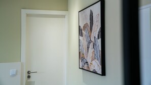 Ein Korridor mit einer Tür links und einem gerahmten Kunstwerk an der Wand.