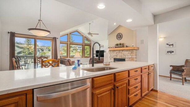A spacious kitchen with a large island, wooden cabinets, and a stone fireplace. - Hot Tub, King Beds, Mountain Views on Balcony & Patio (Estes Park)