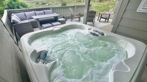A hot tub with a built-in table and chairs, surrounded by a wooden deck and a covered seating area. - Hot Tub, King Beds, Mountain Views on Balcony & Patio (Estes Park)