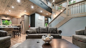 Una sala de estar moderna con una mesa de centro de madera oscura, un sofá de cuero gris y un cuenco con adornos decorativos.