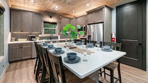 Una cocina moderna con armarios de madera, una isla blanca y un refrigerador de acero inoxidable.