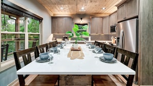 Una cocina moderna con techo de madera, ventanas amplias y una mesa de comedor preparada para seis personas.
