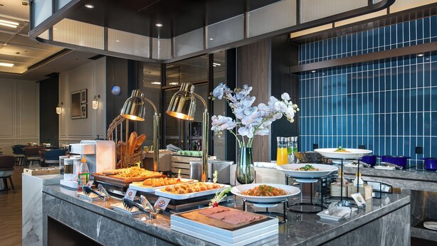 Disposição de buffet com diversos alimentos e um vaso de flores brancas.